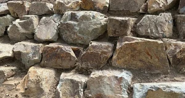 Coldstream stone retaining wall rich in rust, brown and gold, built without mortar