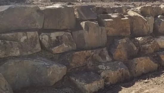 Low Coldstream stone retaining wall coursed along a garden edge in warm brown tones