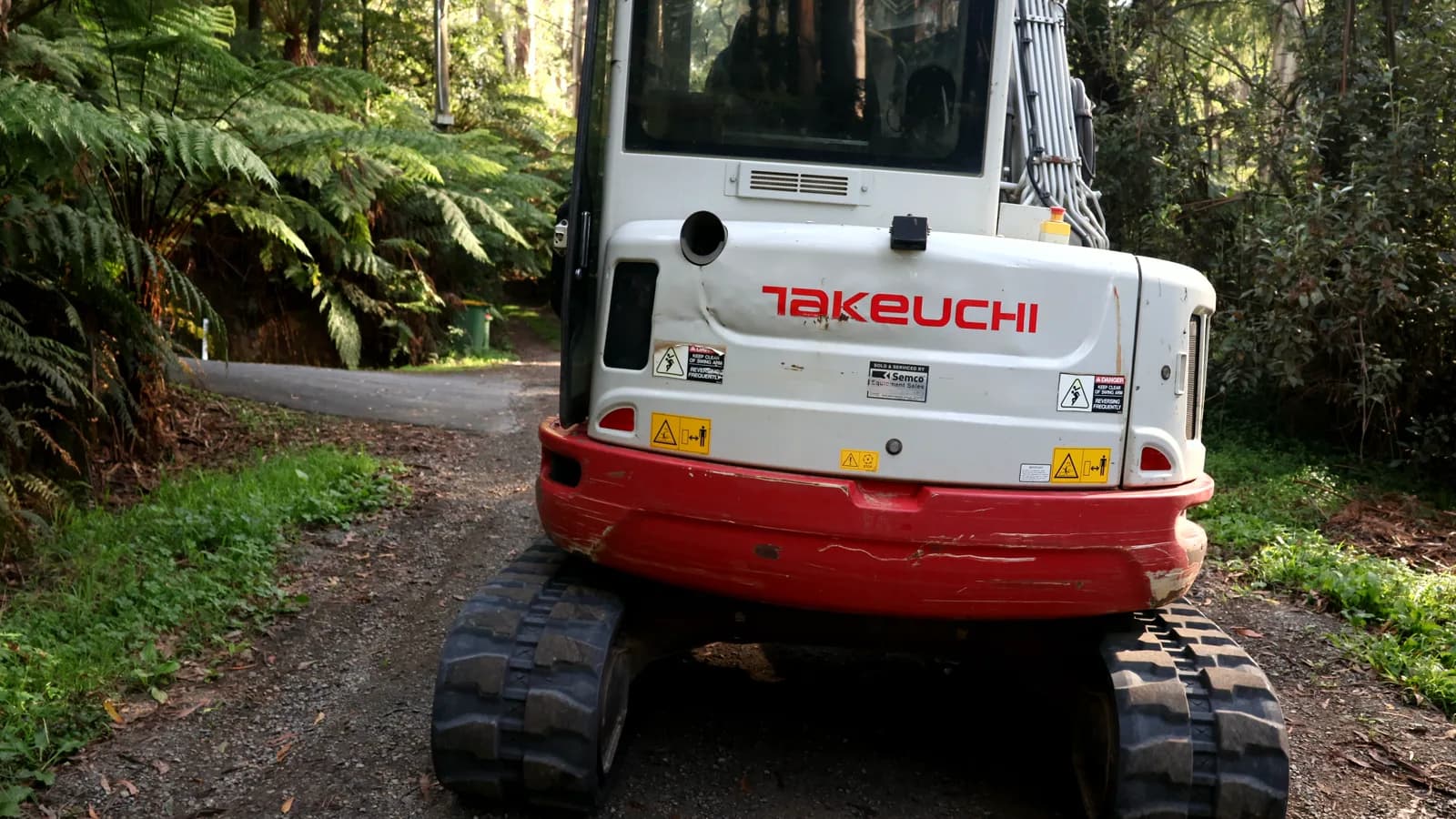 Takeuchi TB257FR compact excavator parked on a forested track in the Dandenong Ranges