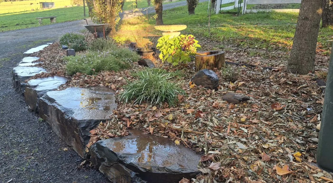 Slate stone garden bed edging curving through an autumn-lit yard, built by Rock'n Earthworks